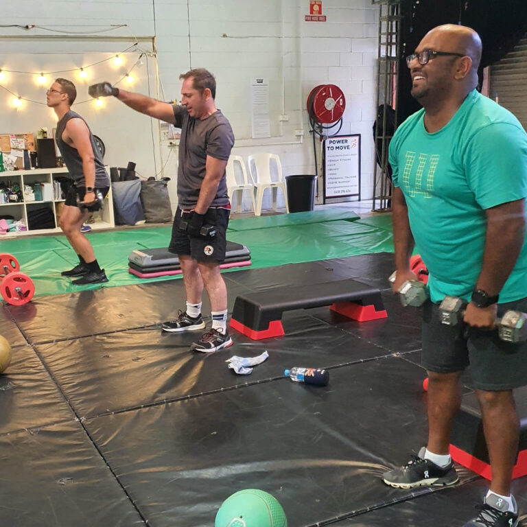 NDIS client with vision impairment lifting dumbell weights with other clients.