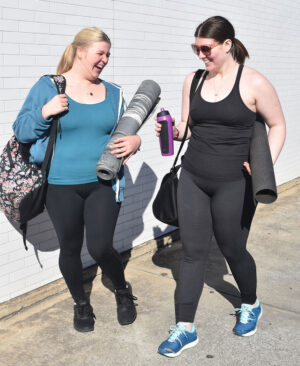 Two girls walking to class with their yoga gear.