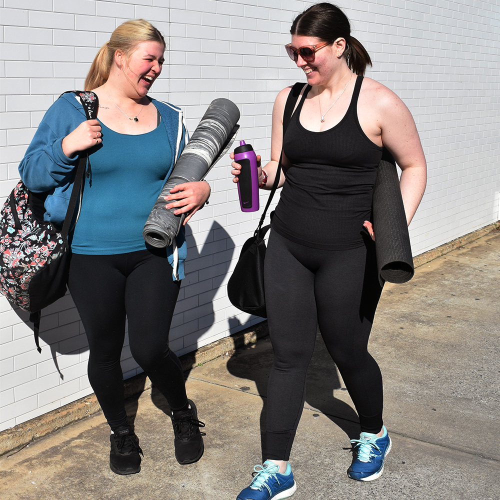 Two ladies with yoga mats walking to yoga class.