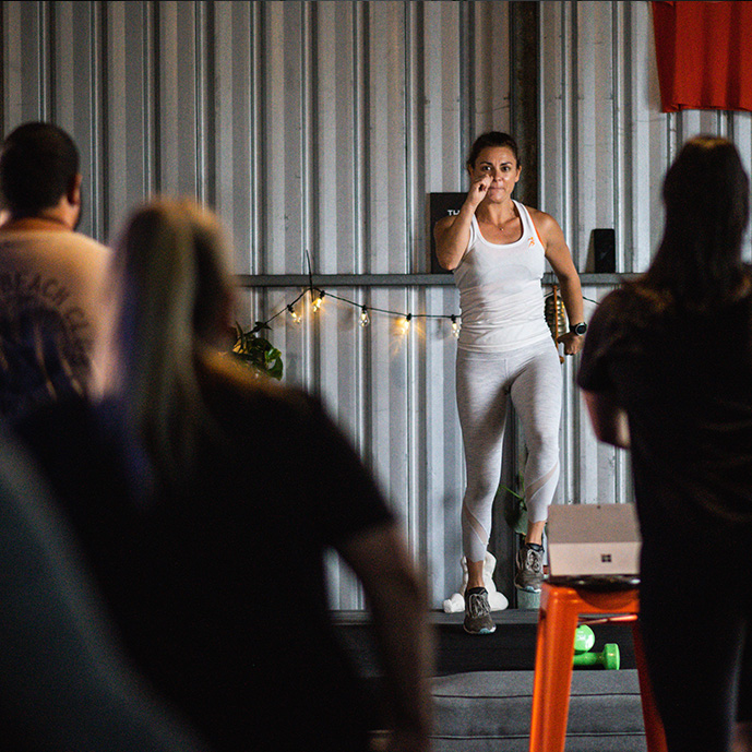 Trainer leading a HIIT class from the stage.