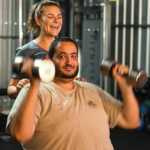Man lifting dumbbells with his personal trainer.