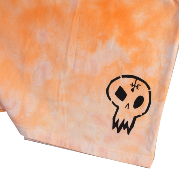 Close up of a black cartoon skull outline on orange tie dye fabric.